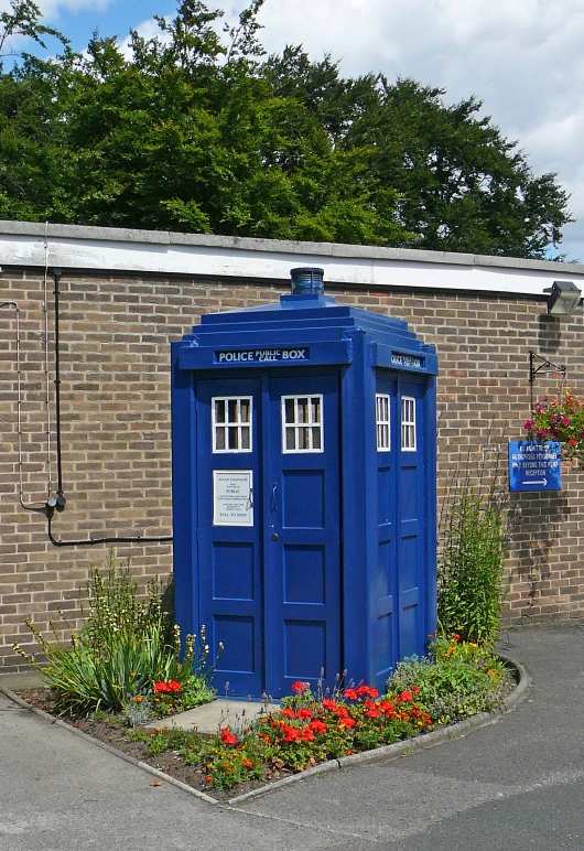 a small red brick building with a blue phone booth in front of it