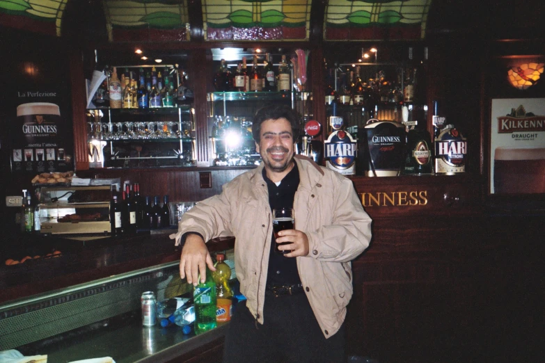 man at bar with drink in hand and smiling