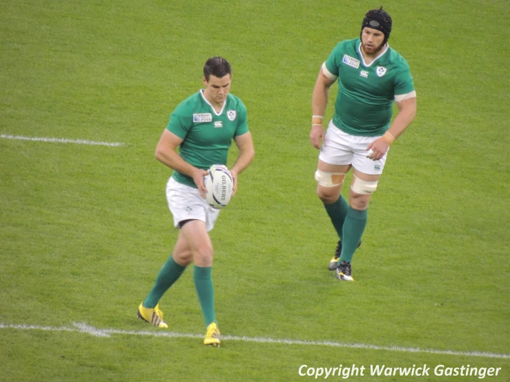 two men in green and white jerseys with a rugby ball