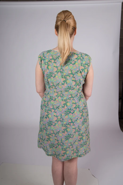 a woman wearing a floral dress standing in front of a backdrop