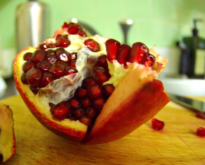 a cut open pomegranate sitting on top of a wooden  board