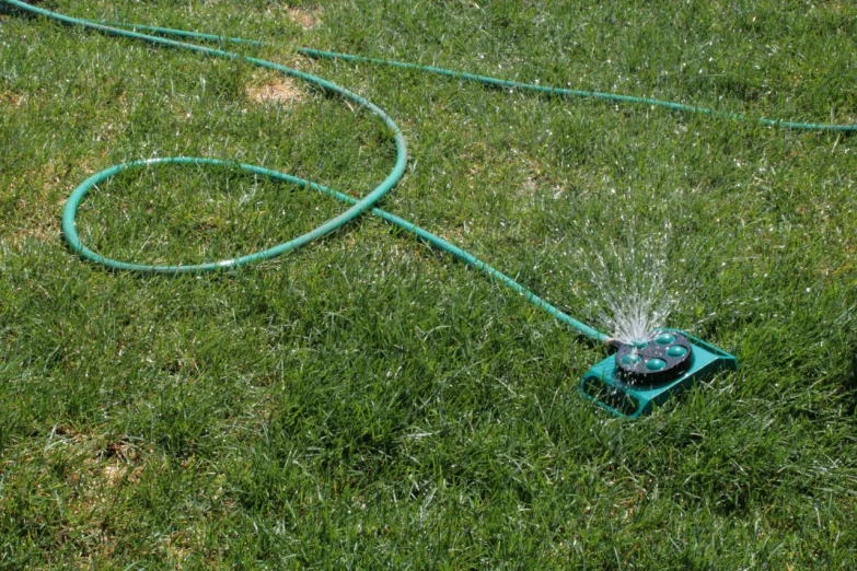 a water hose connected to a lawn with a small power cord attached to it