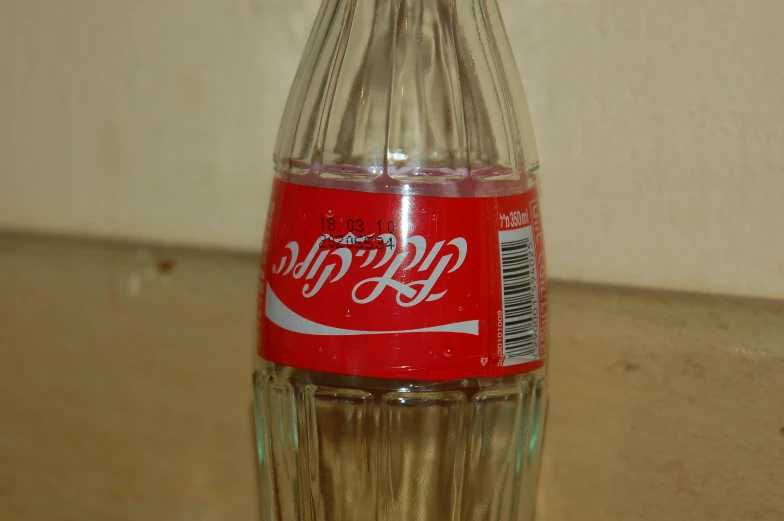 a close up of a coke bottle with a drink in it