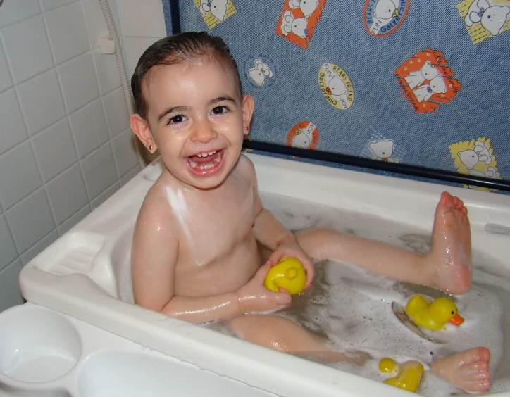 young child enjoying bath with rubber ducks