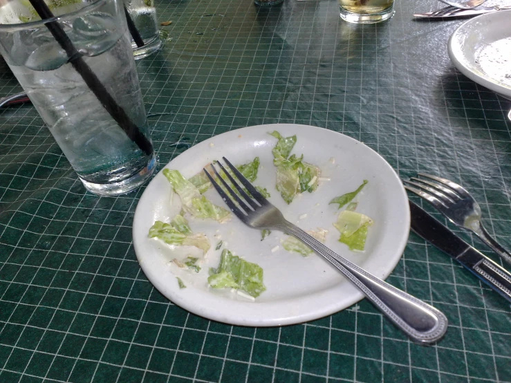 a white plate of vegetables and cutlery on a table