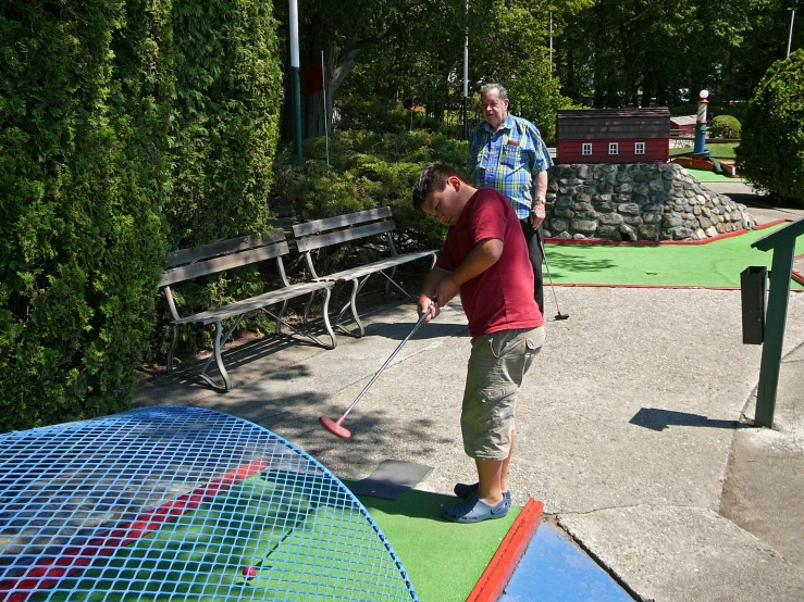 man holding golf club over a colorful painted putting green