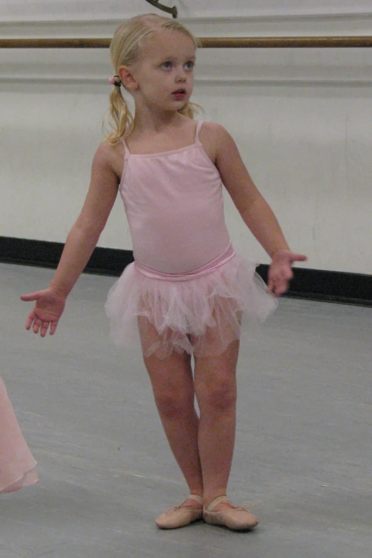 a  in a pink dress standing with her hands outstretched