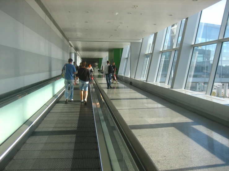 people are walking on the walkway next to a huge window