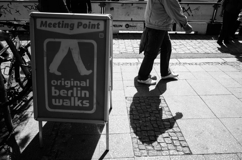 black and white po of a man walking next to a sign