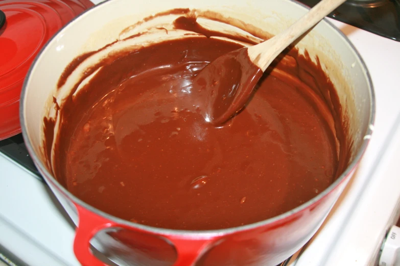 a red sauce pot is filled with  chocolate