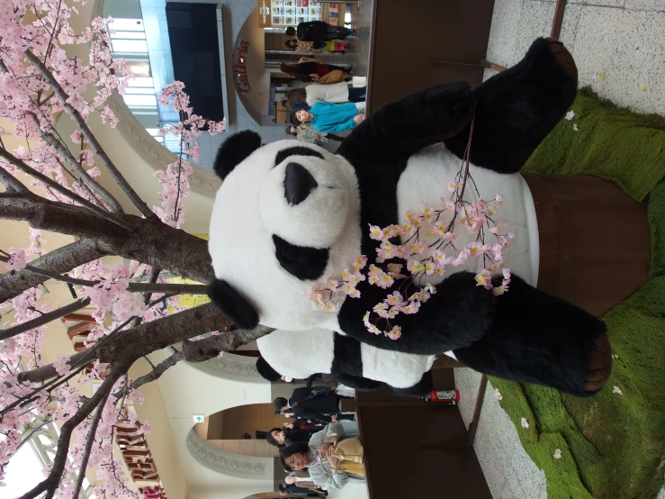 the giant stuffed panda bear is holding a flower planter
