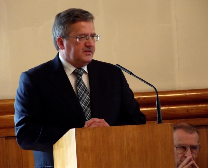 a man speaking into a podium wearing a suit and tie