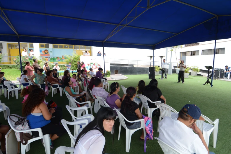 group of people sitting under tent on a tennis court