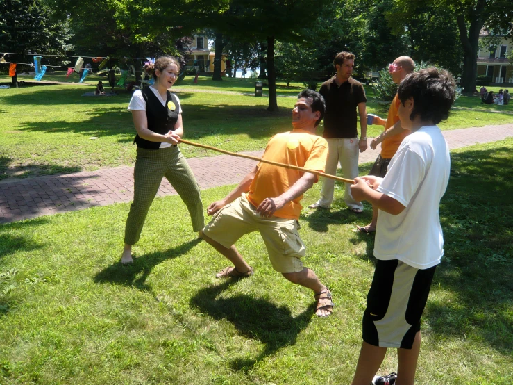 people standing around in the grass with one man pulling the cord with his hands