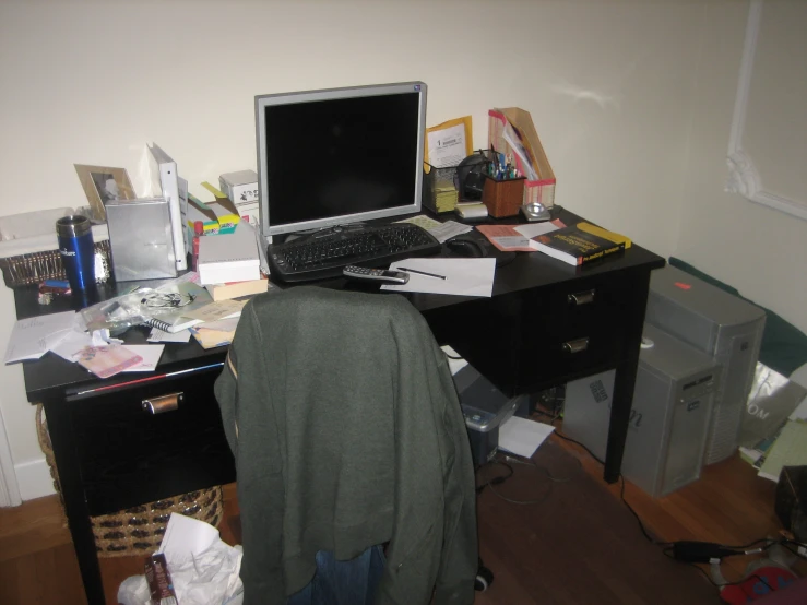 a cluttered desk has an open laptop and messy shelves