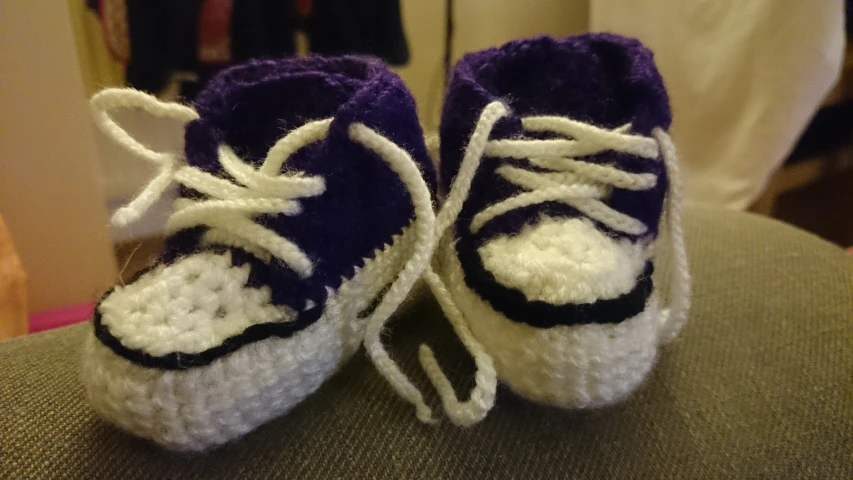 purple baby shoes are sitting on the arm of a child