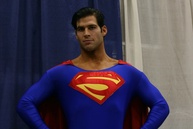 a man in a superman suit stands in front of curtains