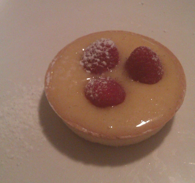 a small yellow pastry with raspberries on top