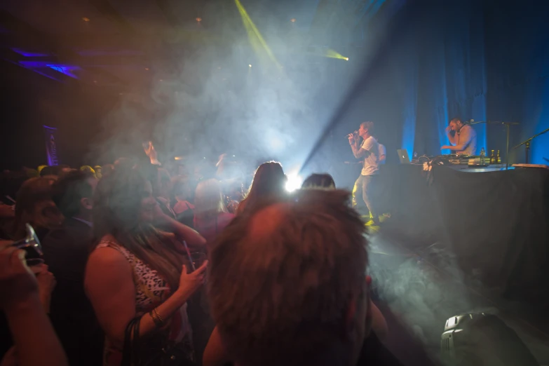 a group of people standing around watching a person on a stage