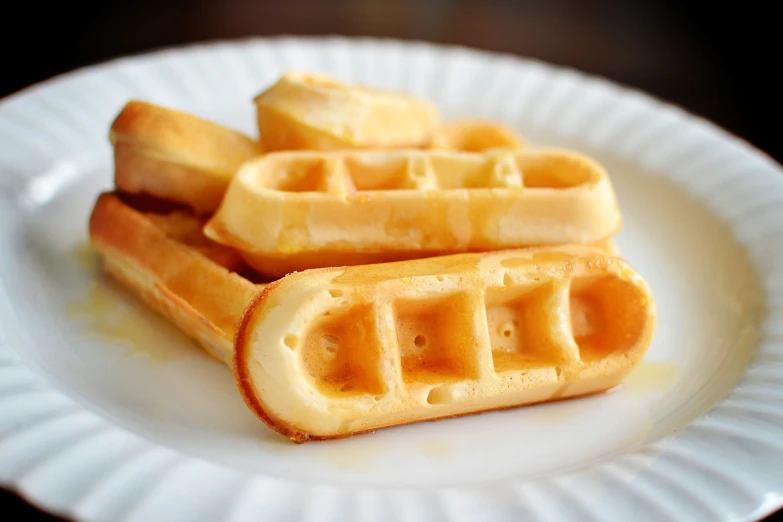 two waffles sitting on a white plate, the other half is half eaten