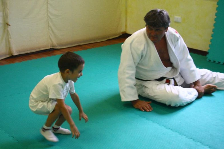 an adult in white shirt and a child on blue mat