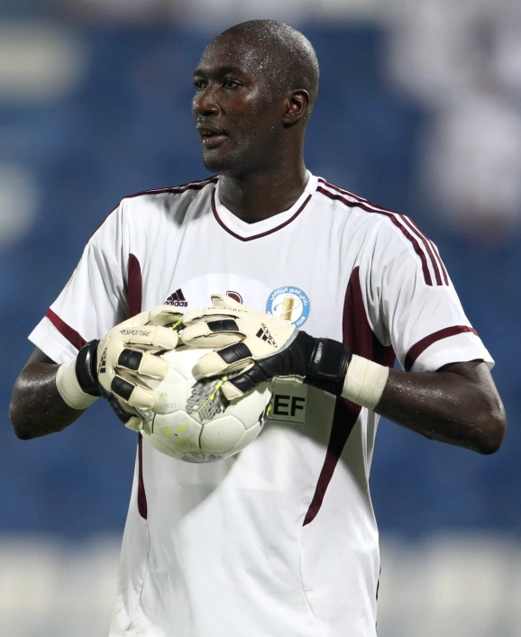 a male soccer player is wearing a white and maroon uniform