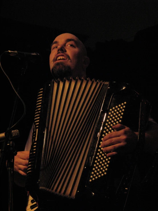 a man plays an accordion in front of a microphone