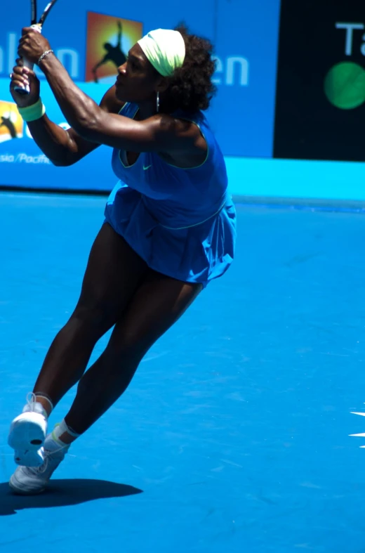 an attractive woman holding a tennis racquet on a blue tennis court
