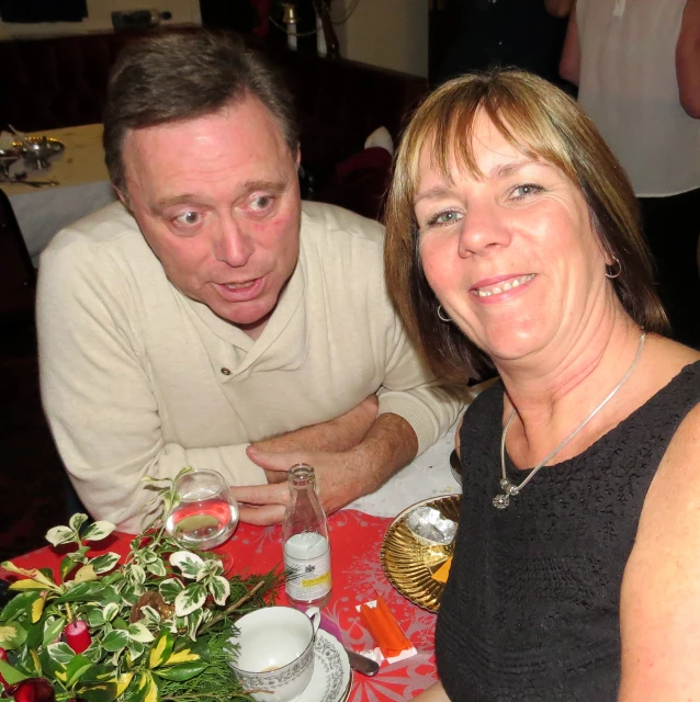 a woman holding a glass of wine while a man looks on