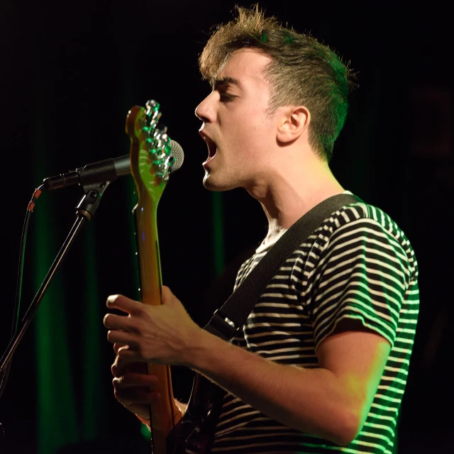 a man standing on stage singing with his guitar