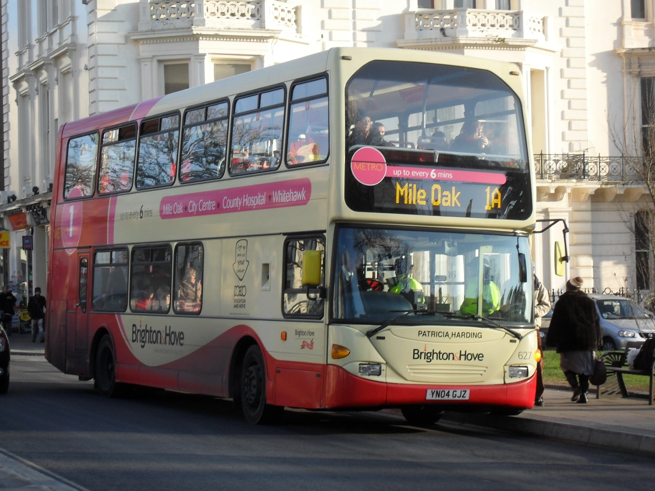 the double decker bus is in traffic next to a tall building