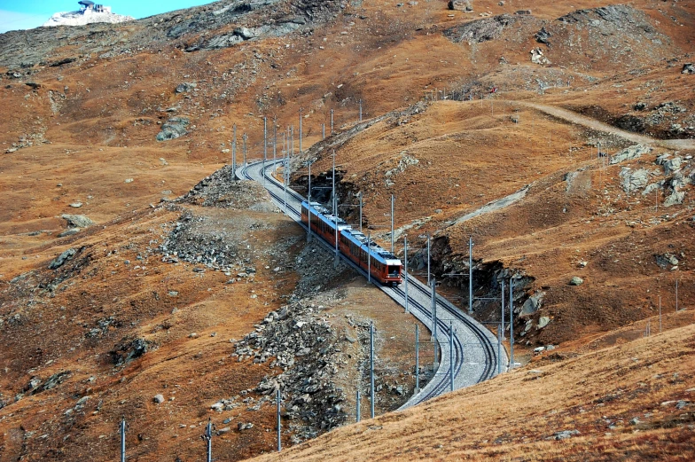 a passenger train going along tracks near a mountain