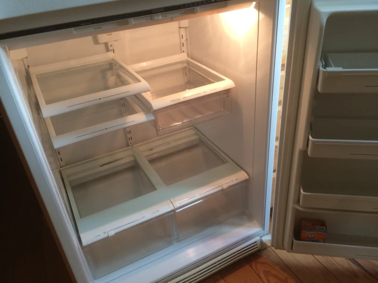 a white refrigerator is opened and shows several pieces of empty