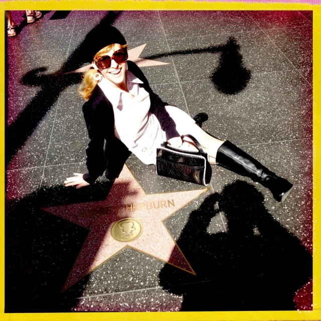 a woman wearing sunglasses laying on the star of hollywood
