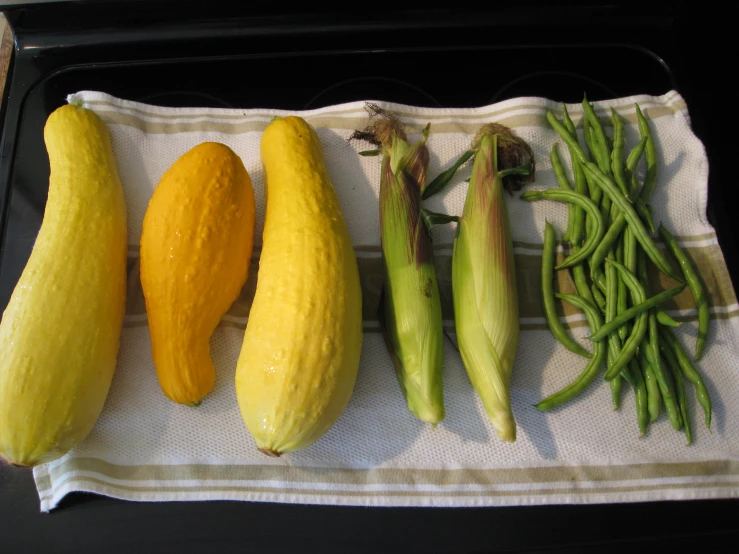 four squash, beans and long bean pods on a towel