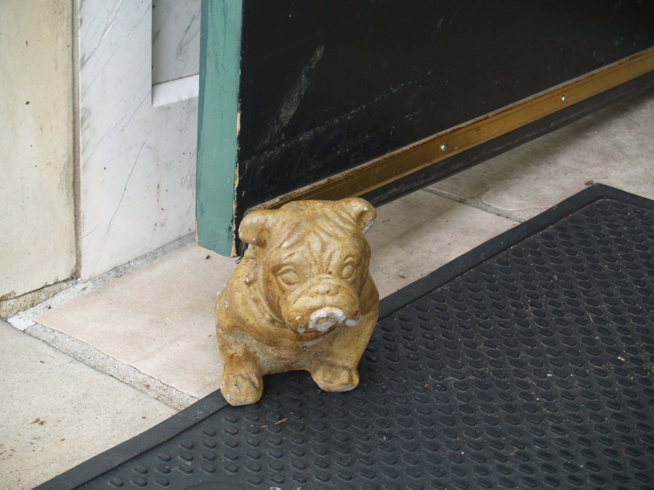 a small figurine sitting on the ground in front of a door