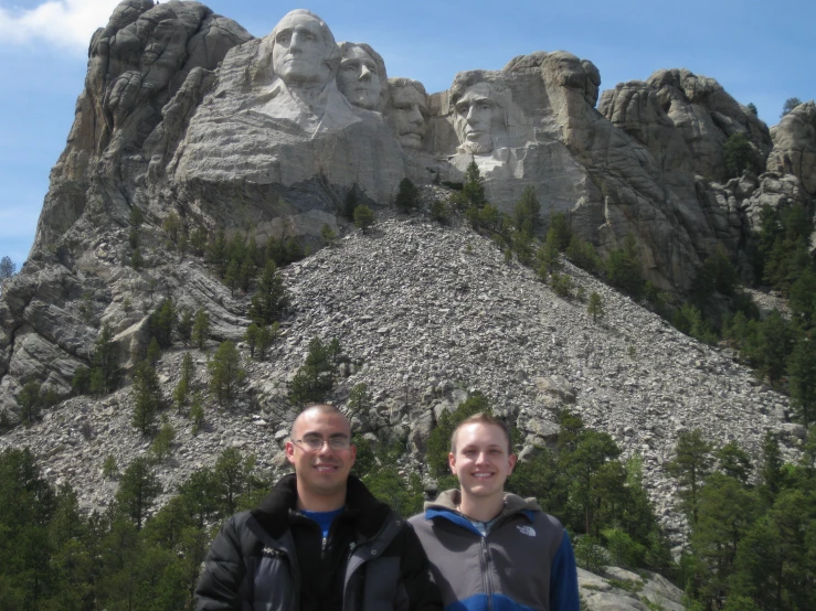 a man and woman pose for a picture in front of some large rock formations