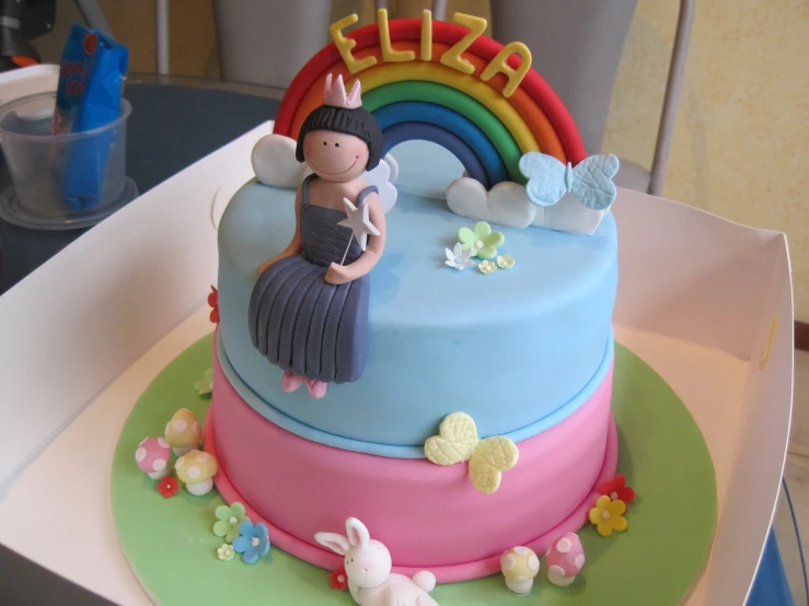 a cake with an image of a girl in a dress with her hands up on the top tier