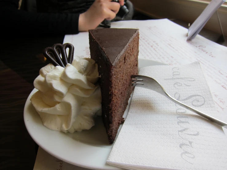 there is a large piece of cake on a plate with a fork and whip cream