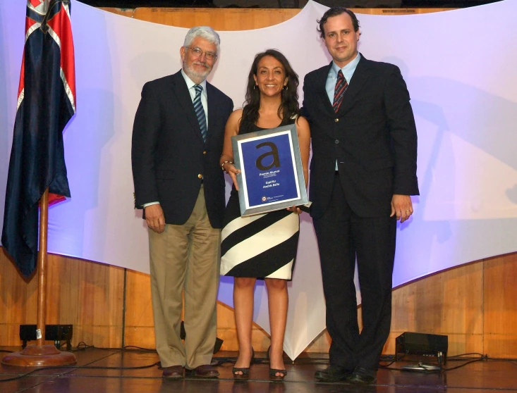 a man standing next to two women, holding a framed award