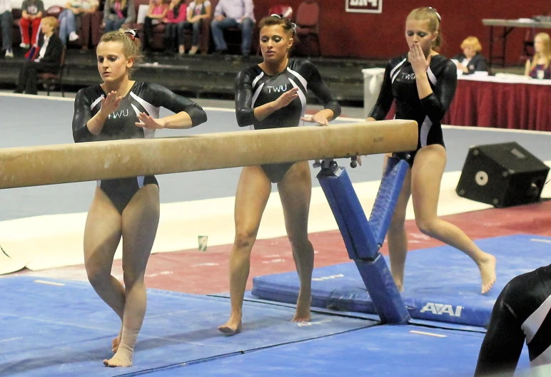 four women are on the balance beam during a competition