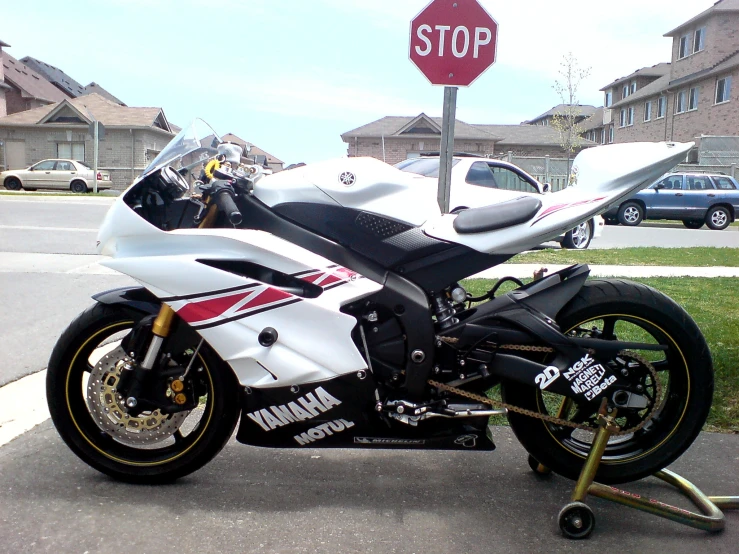 white motorcycle sitting in the street next to stop sign