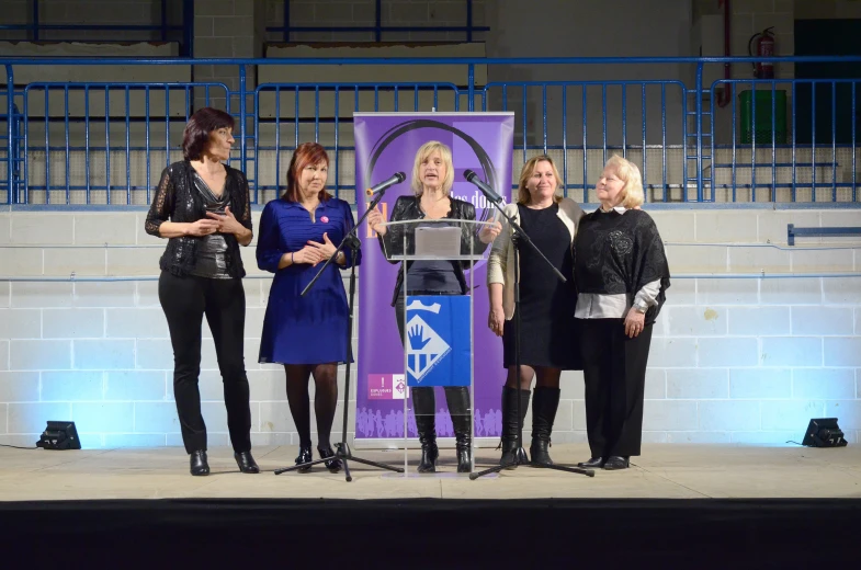 three woman stand by a podium in front of a sign