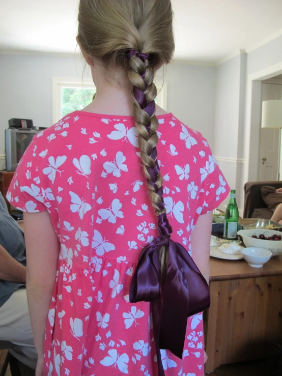 little girl in pink dress holding two ids in her hair