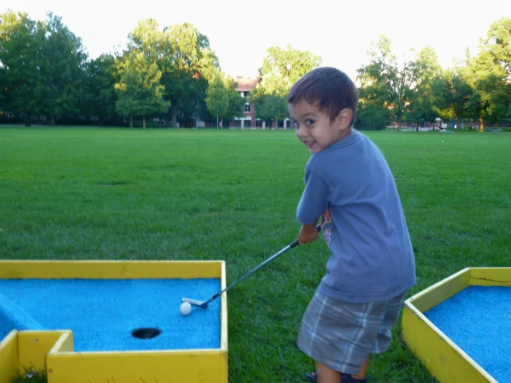 a small boy holding a baseball bat near a ball