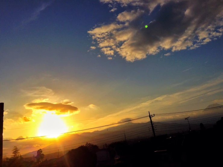 the sun is setting behind a chain linked fence