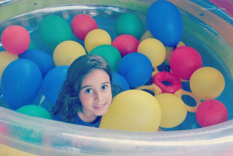 a woman standing in a pool filled with balloons