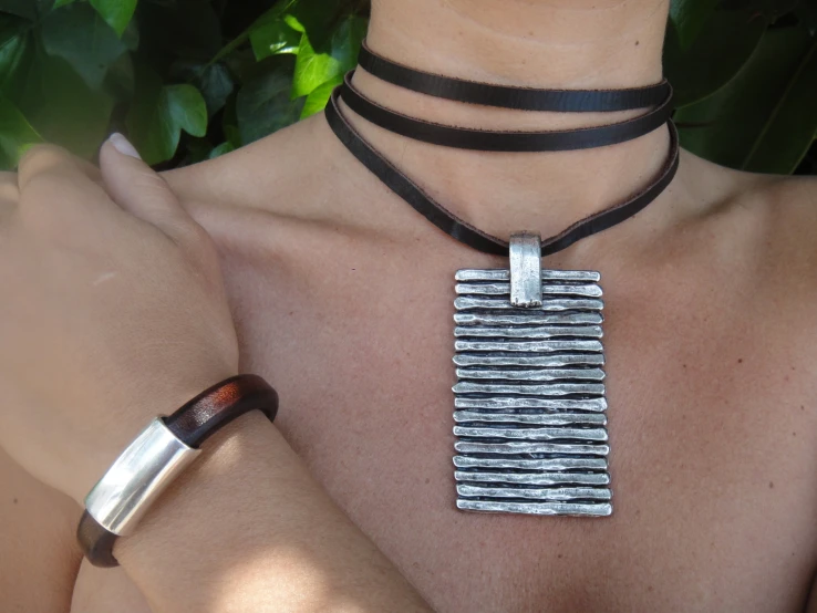 a silver metal bar is on top of a brown leather necklace