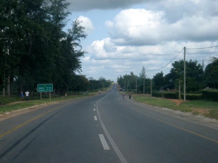 a long straight road with some people walking along it