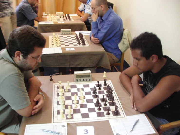 a group of people sitting around a table playing chess